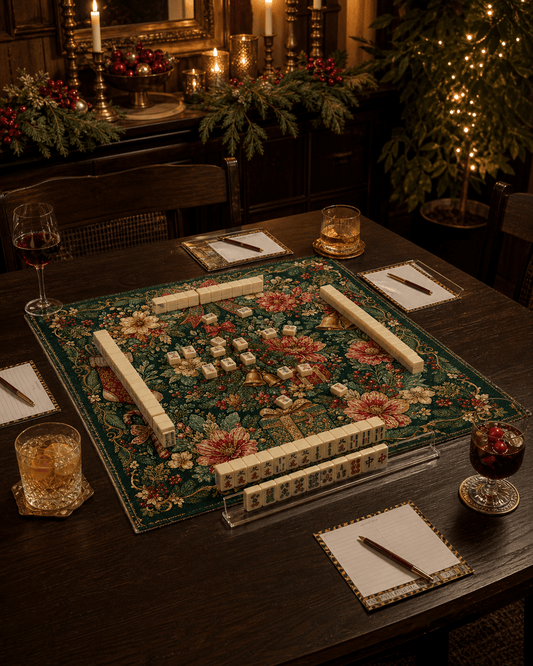 Dark green Christmas mahjong mat prepared for a game beside holiday greenery, candles, and a decorated tree.