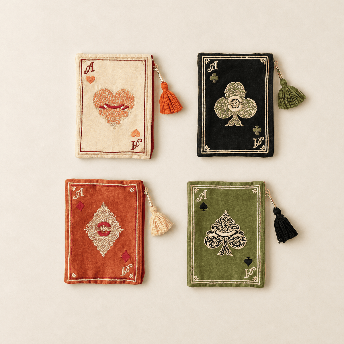 Four handmade embroidered playing card pouches in cream, black, terracotta, and olive green