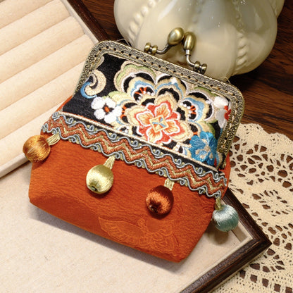 Orange vintage coin purse with floral embroidery, brass kiss-lock clasp, and hanging fabric beads.