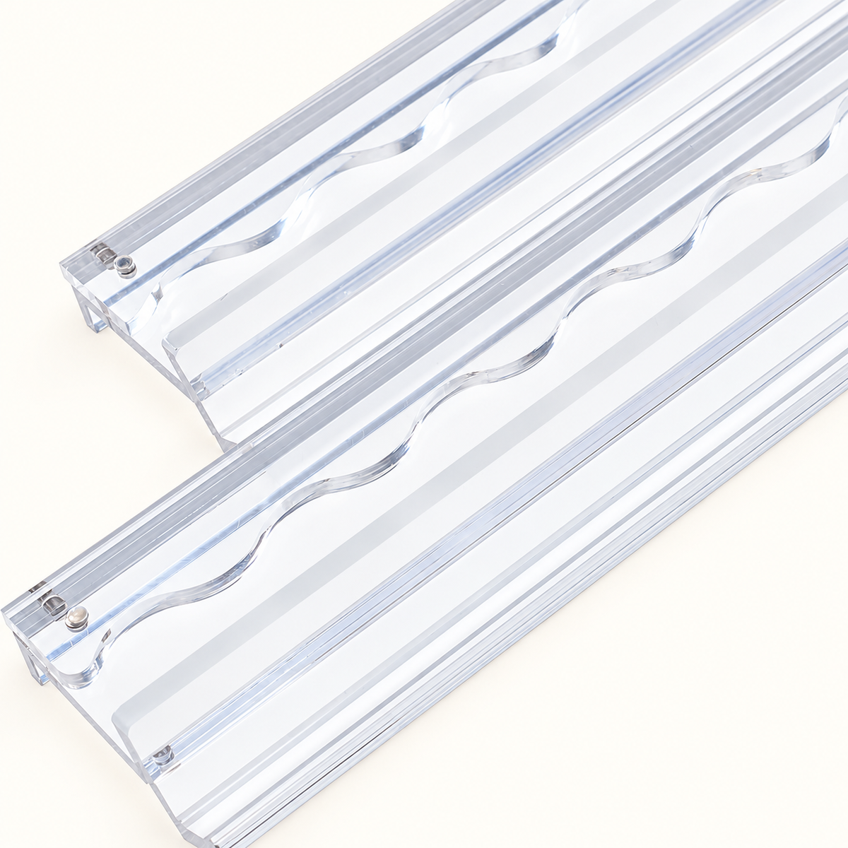 Close-up of two clear mahjong racks showing their tile ledges, scalloped pushers and round connectors.