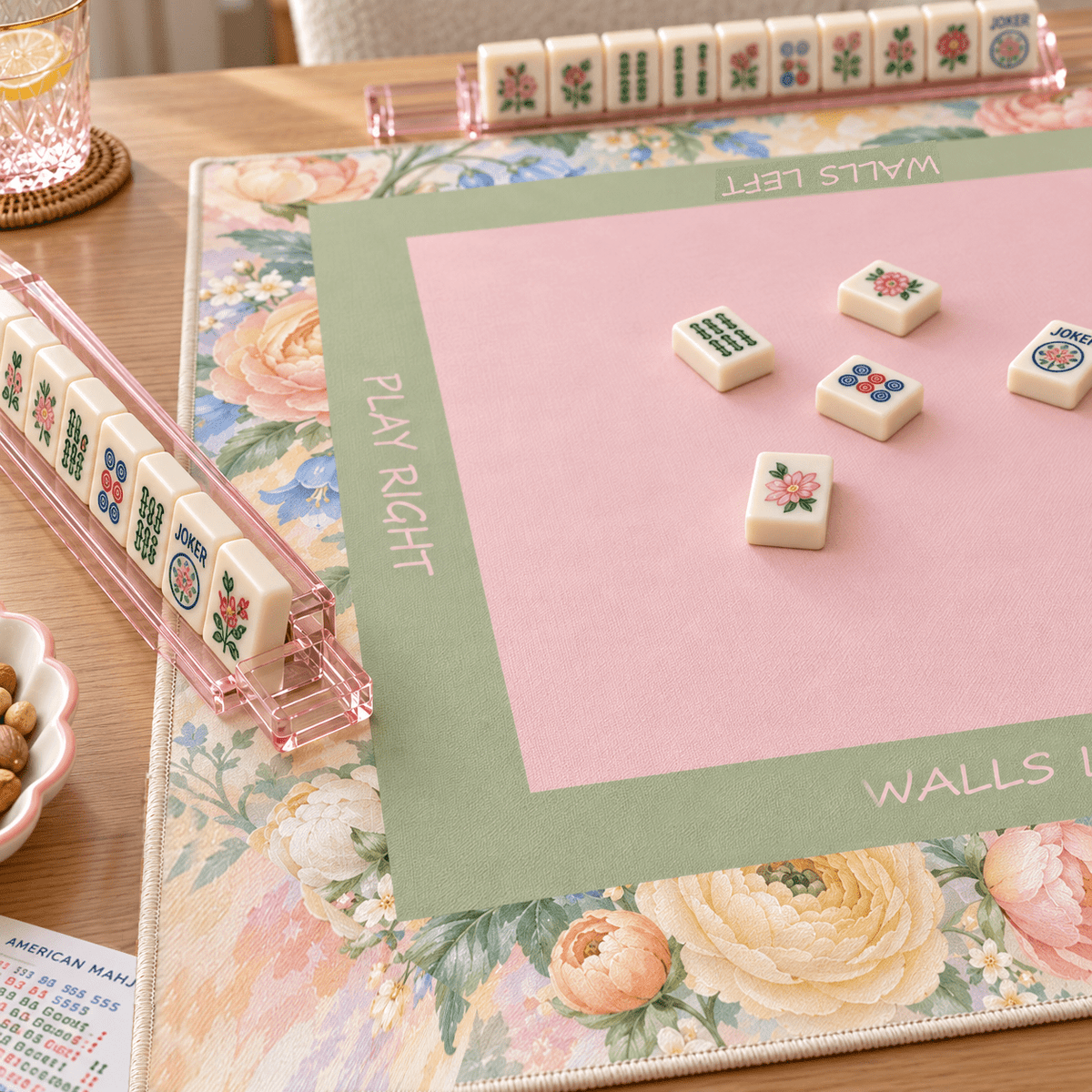 Angled view of the Pastel Bloom Mahjong Mat showing its pink center, green frame, floral border, and mahjong tiles.
