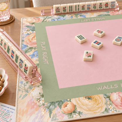 Angled view of the Pastel Bloom Mahjong Mat showing its pink center, green frame, floral border, and mahjong tiles.