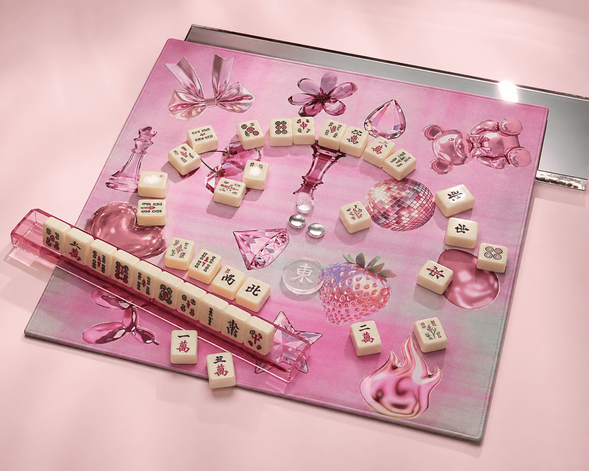 Pink Y2K mahjong mat arranged with loose mahjong tiles, a tile rack, dice, and a mirrored backdrop.