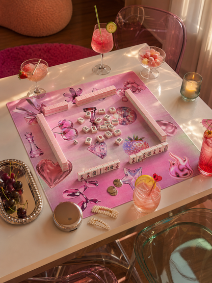 Pink Y2K mahjong mat set for play on a glass table with colorful drinks and retro decor.