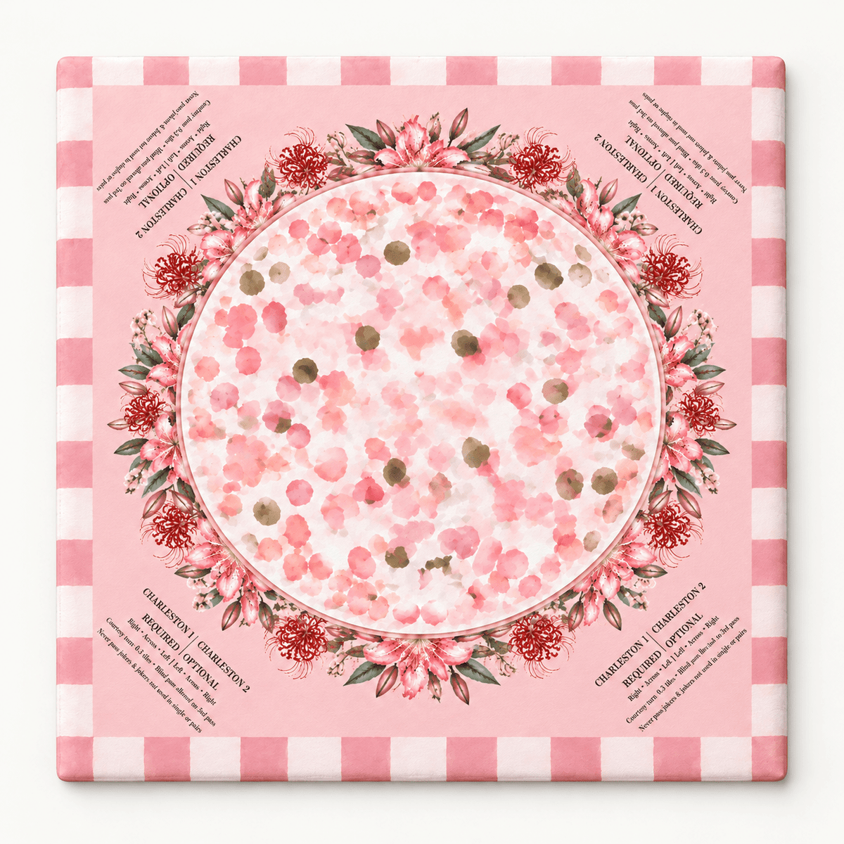 Square pink mahjong mat with a circular floral wreath, scattered blossoms, and a pink checkered border, displayed against white.