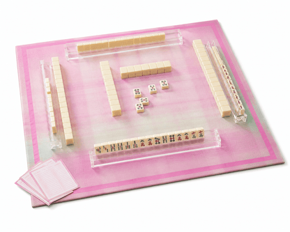 Pink plaid mahjong mat displayed with mahjong tiles, clear racks, dice, and scorecards.