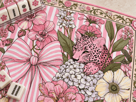 Close-up of the pink leopard and striped bow floral mahjong mat showing its fabric texture, pink stitched edge, and mahjong tiles beside a clear rack.