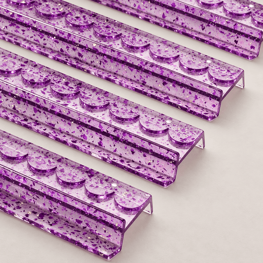 Close-up of four purple acrylic mahjong racks showing scalloped edges and gold foil flecks